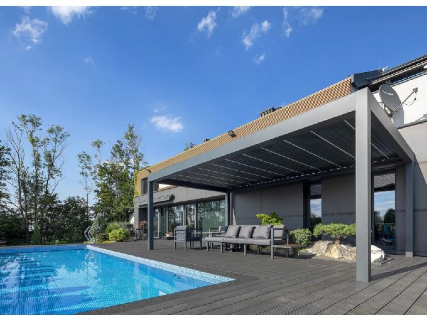 Nowoczesna, szara pergola bioklimatyczna SUNBEAM 1400 na tarasie przy basenie z meblami ogrodowymi