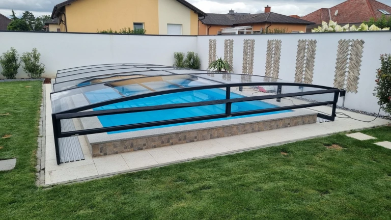 Nowoczesna, niska osłona basenowa z czarną konstrukcją nad basenem ogrodowym