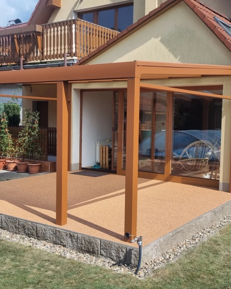 Nowoczesna brązowa pergola z aluminium ze szklanymi ścianami na tarasie domu jednorodzinnego.