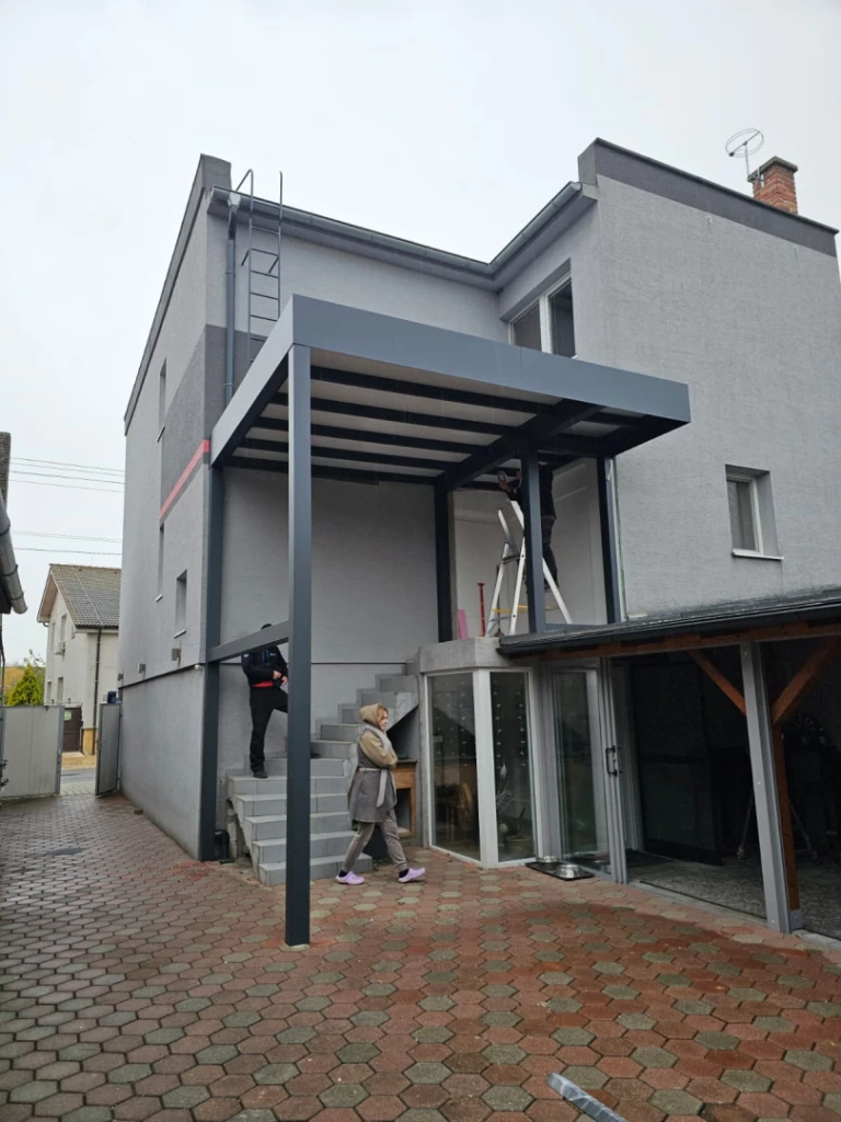 Nowoczesna szara pergola z aluminium zamontowana na tarasie domu jednorodzinnego