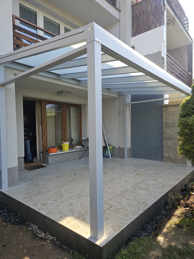 Nowoczesna pergola aluminiowa ze szklanym dachem na tarasie domu jednorodzinnego