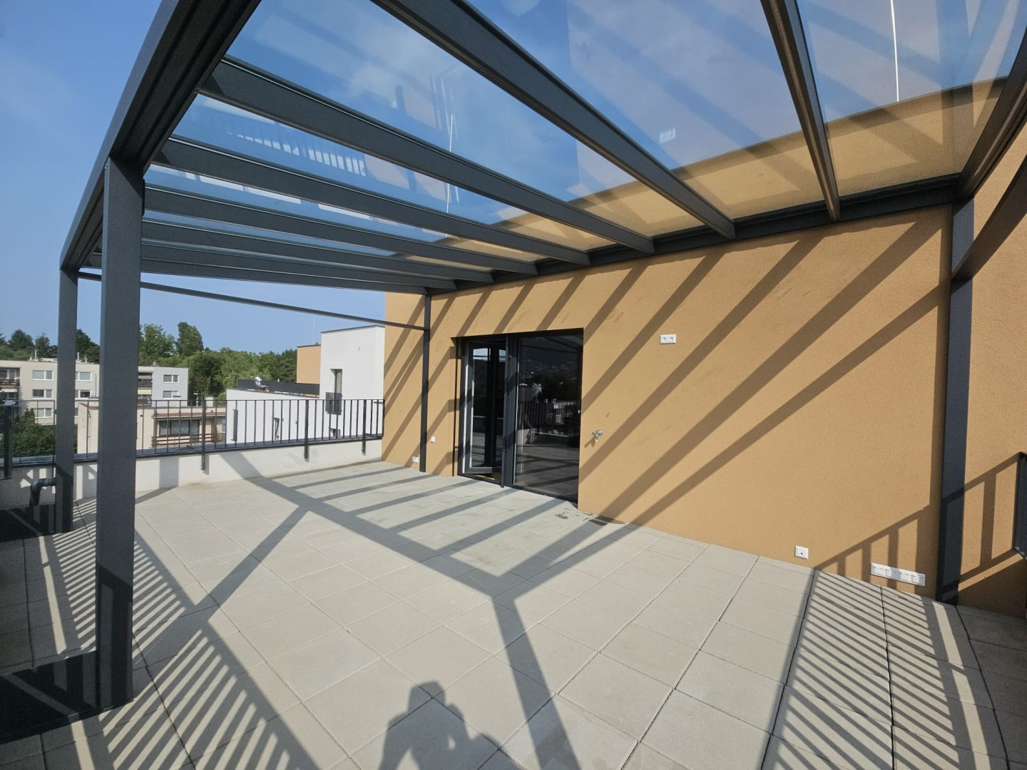 Nowoczesna pergola aluminiowa z przeszklonym dachem na tarasie budynku mieszkalnego
