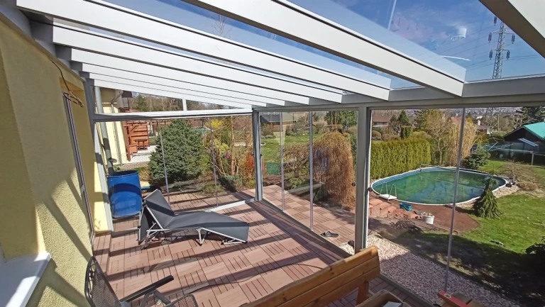 Nowoczesna, przeszklona pergola z aluminium z tarasem i widokiem na ogród z basenem