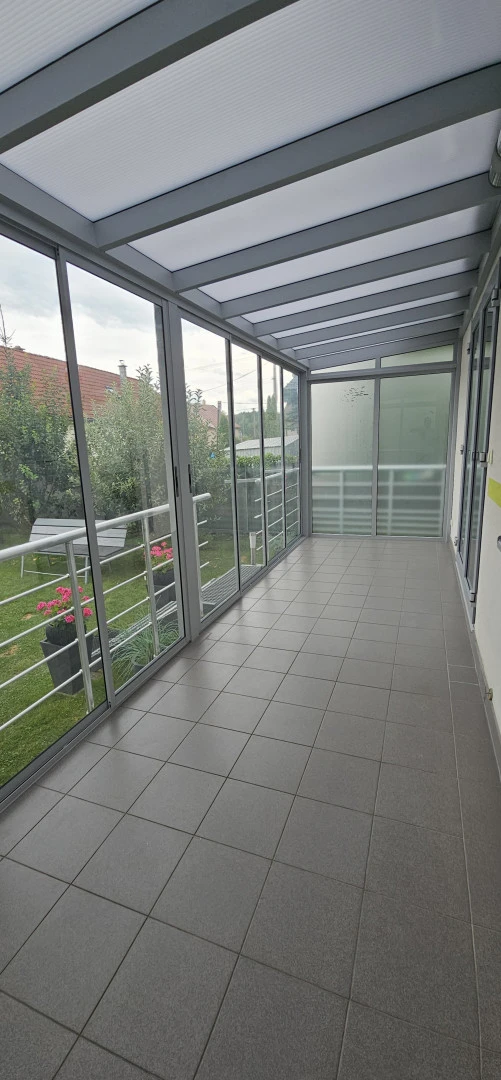 Wnętrze przeszklonej oranżerii z widokiem na zielony ogród