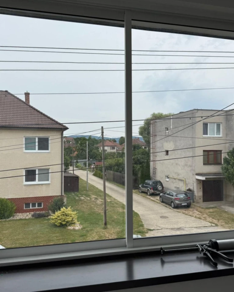 Widok przez nowe przeszklenie na ulicę z domami jednorodzinnymi i samochodami w Skalicy.