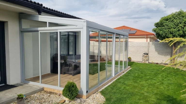 Nowoczesny, przeszklony ogród zimowy z aluminiową konstrukcją, dobudowany do domu jednorodzinnego z ogrodem