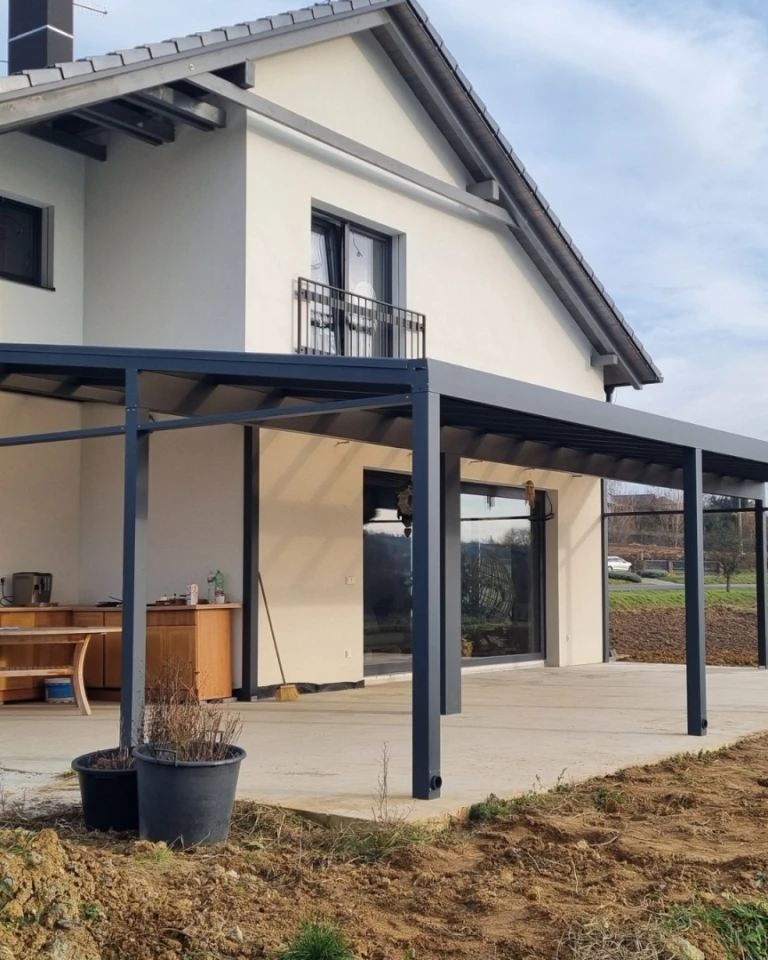 Nowoczesna pergola aluminiowa z ciemnoszarą konstrukcją, wzniesiona przy domu jednorodzinnym