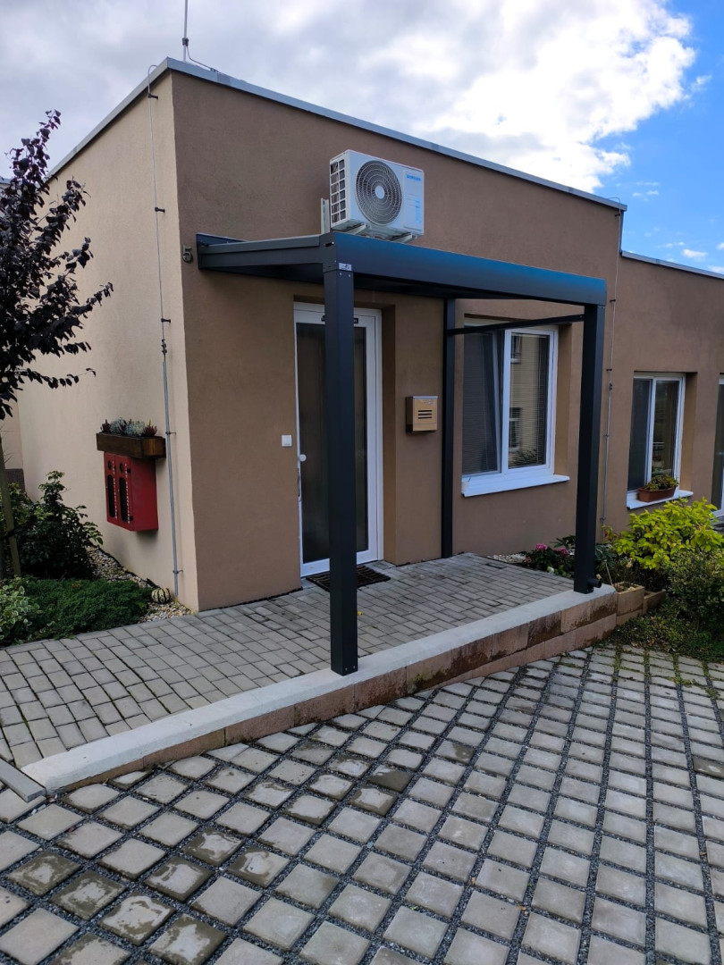 Nowoczesna aluminiowa konstrukcja nad drzwiami wejściowymi do domu jednorodzinnego