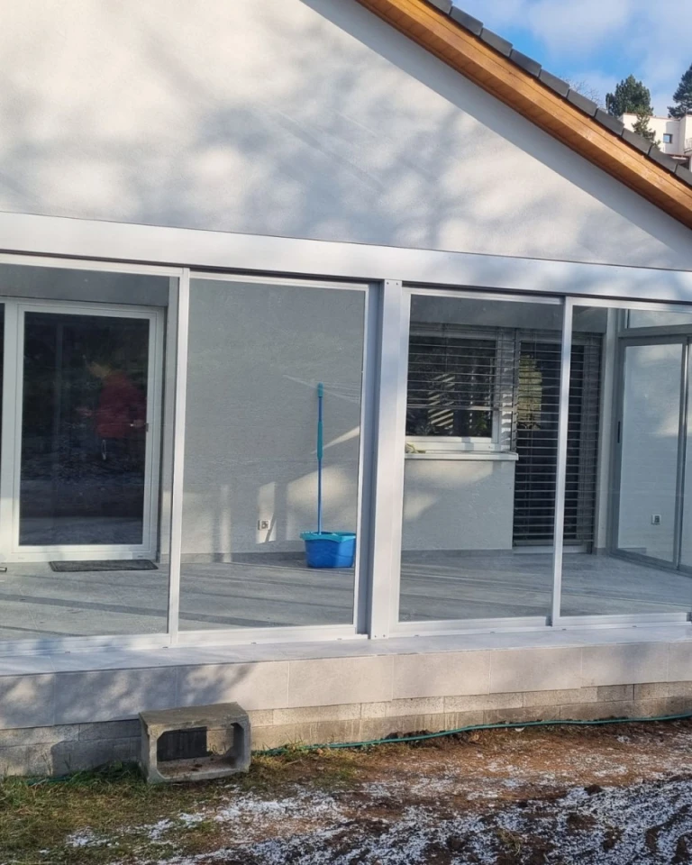 Zaszklony ogród zimowy z aluminiową konstrukcją zamontowany przy domu jednorodzinnym.